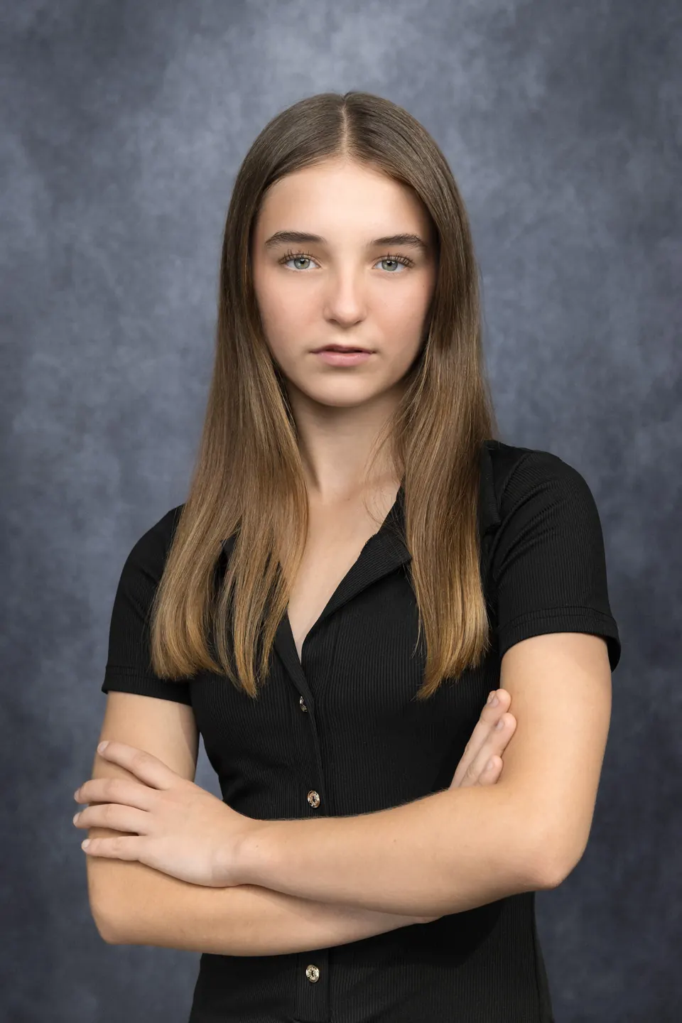 Manon Maindivide headshot in a black shirt with arms crossed, studio background