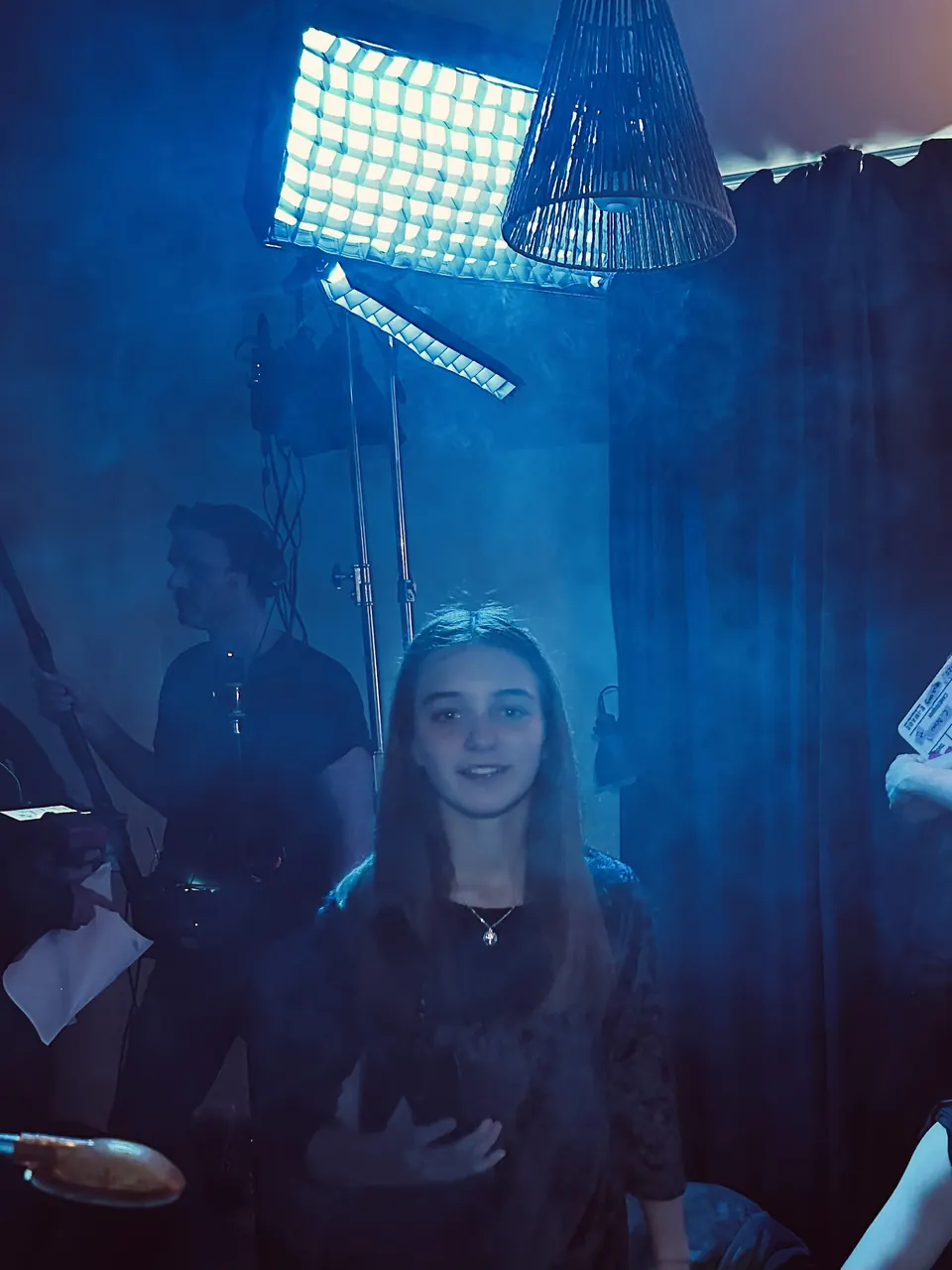 Manon Maindivide on set under blue light with a film lamp and crew in the background