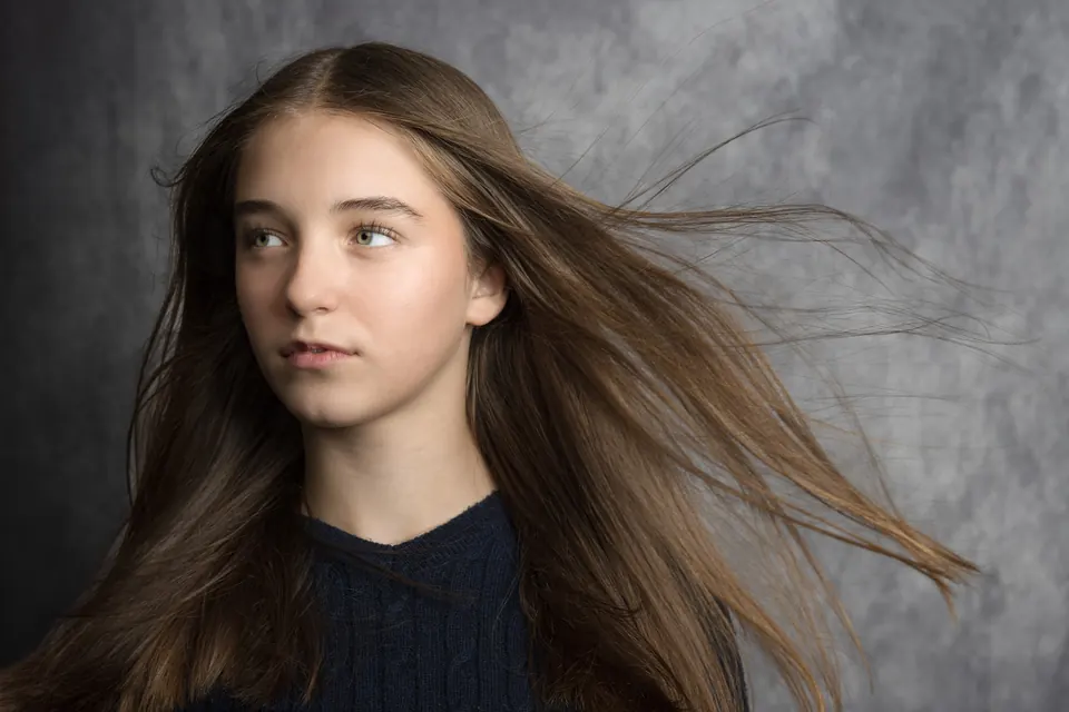 Manon Maindivide portrait with windswept hair against a grey studio backdrop
