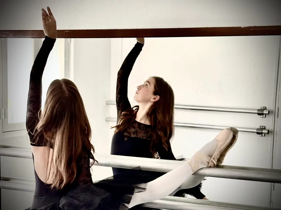 Manon Maindivide ballet stretch at the barre, seen from behind with her reflection in the mirror