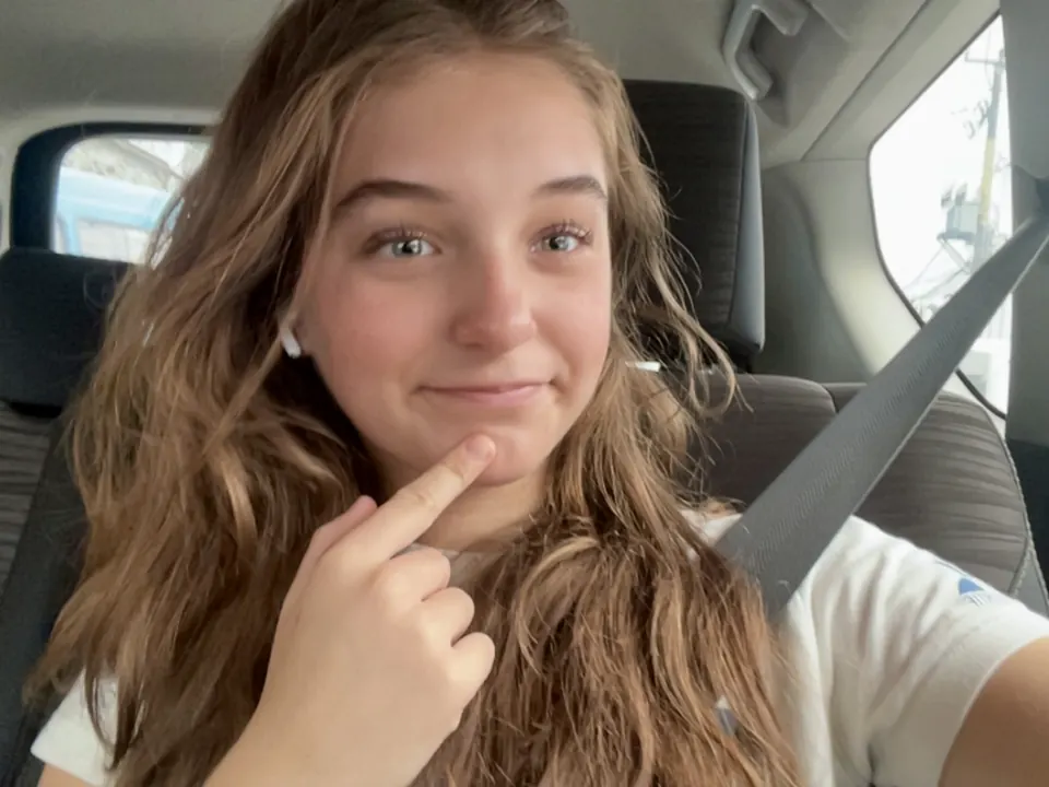 Manon Maindivide casual selfie in a car, finger on her chin with a playful smile