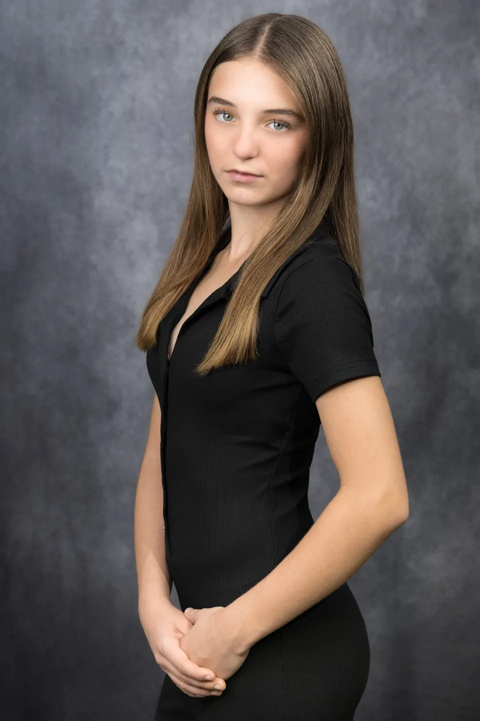 Manon Maindivide headshot in a fitted black top, three-quarter pose against a grey studio backdrop