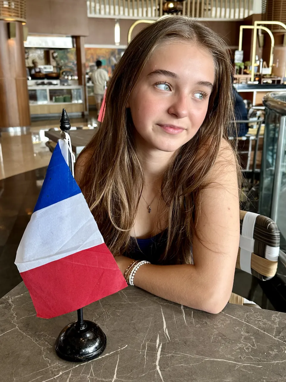 Manon Maindivide casual portrait at a café table next to a small French flag