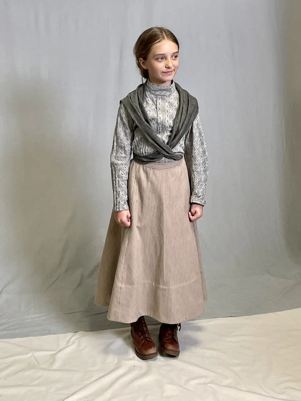 Manon Maindivide in full period costume with a crossed shawl and long skirt, studio backdrop