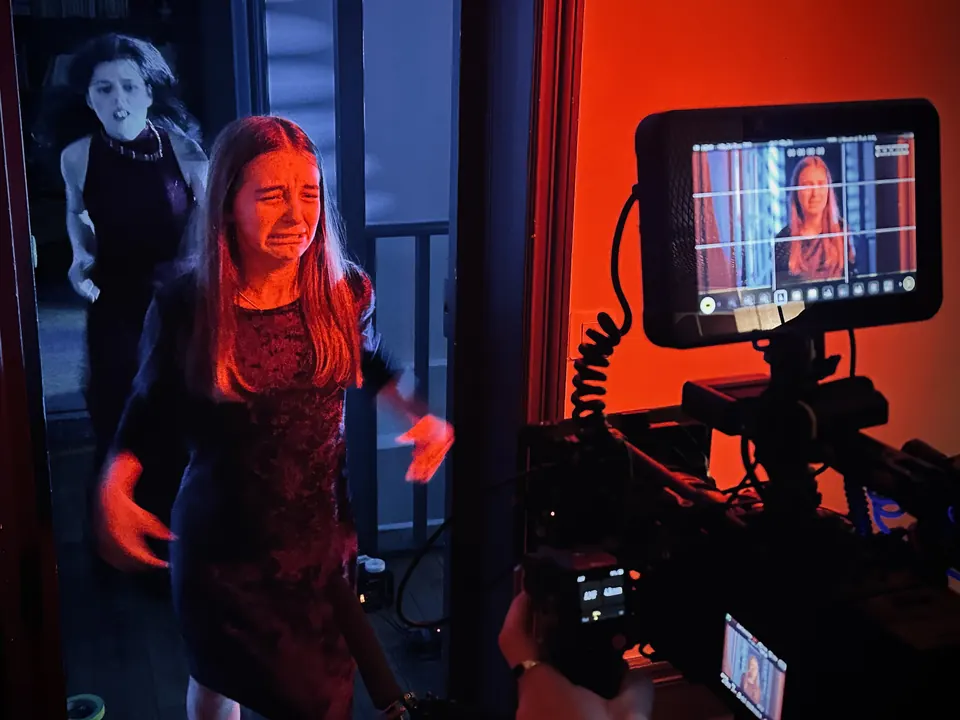 Manon Maindivide on set, crying in a dramatic scene under red lighting with a camera monitor in front