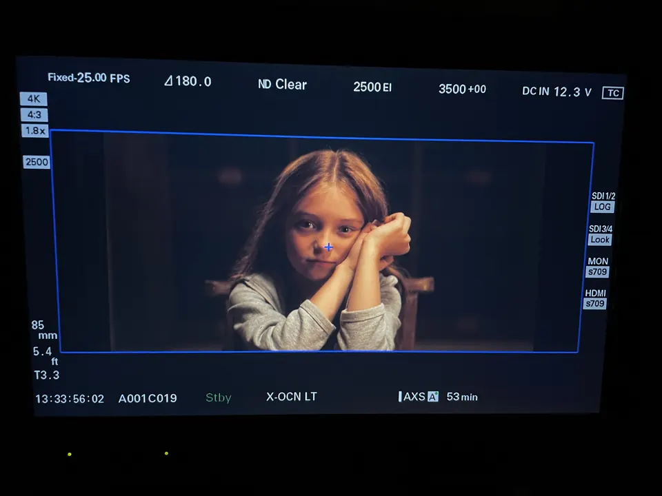 Manon Maindivide on set, chin on folded hands in a scene framed on a camera monitor