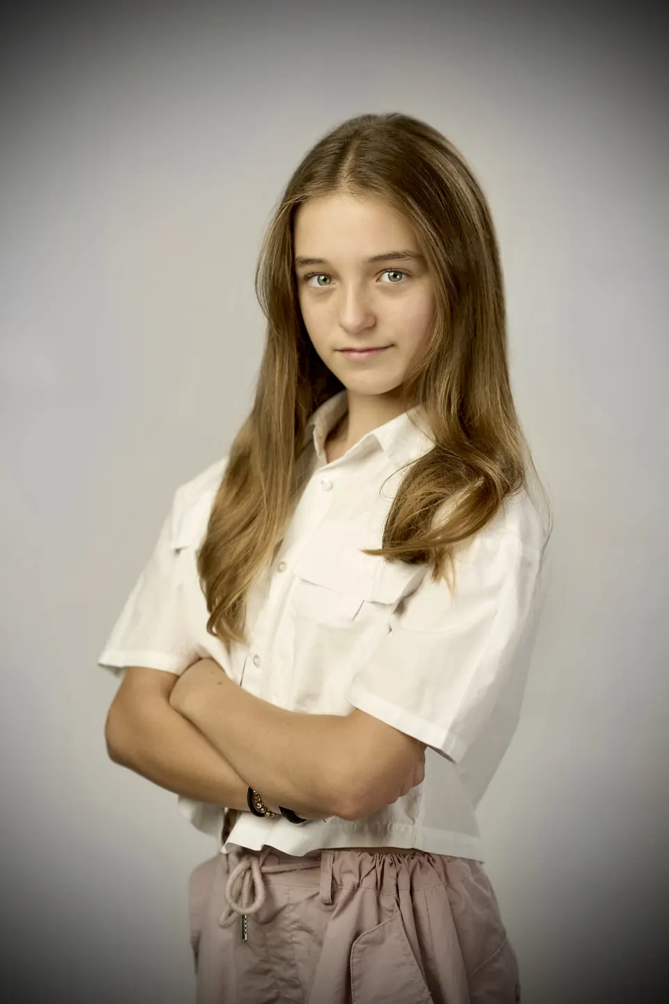 Manon Maindivide headshot in a white shirt with arms crossed against a soft grey vignette