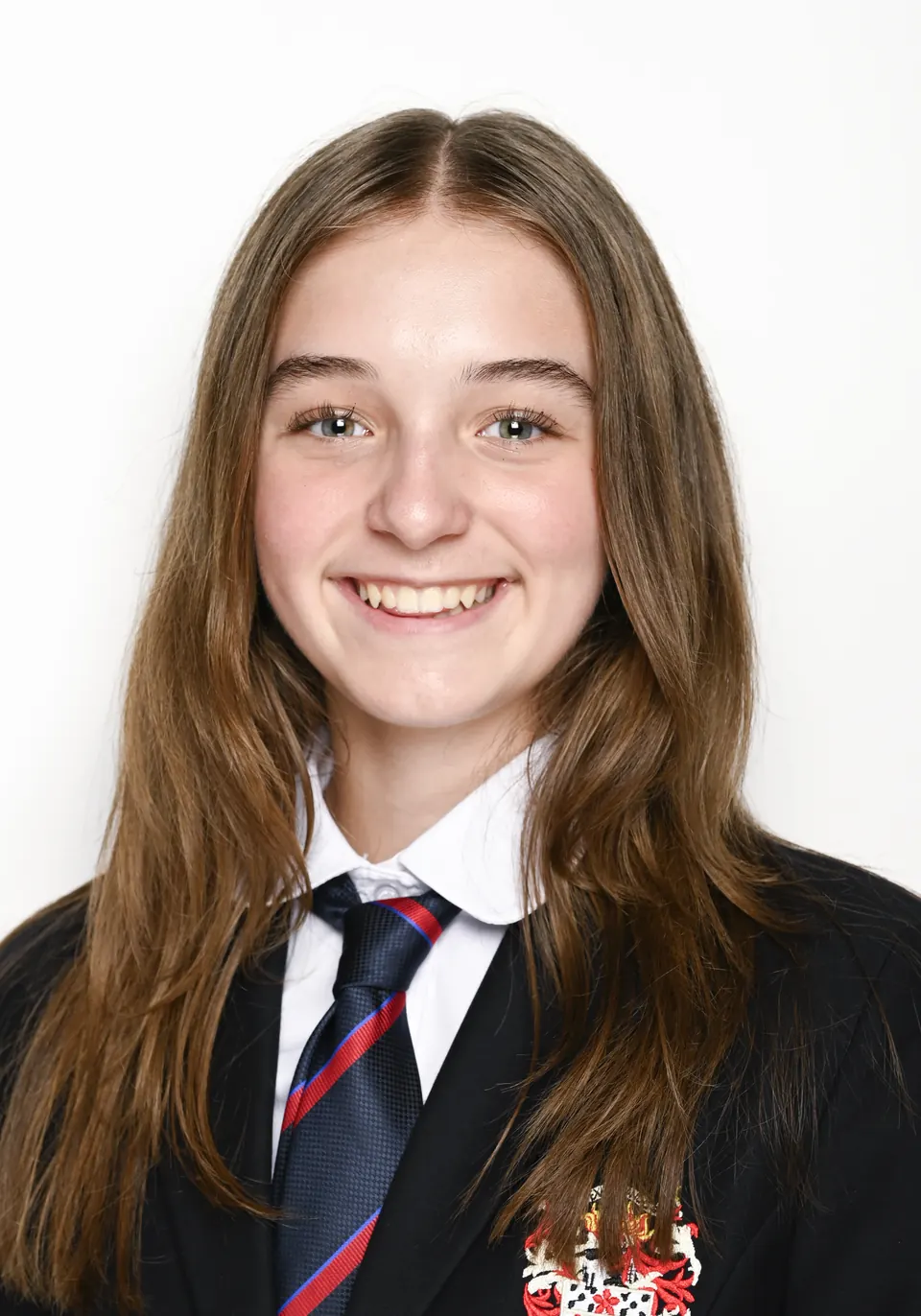 Manon Maindivide headshot smiling in a dark blazer, white shirt and striped tie