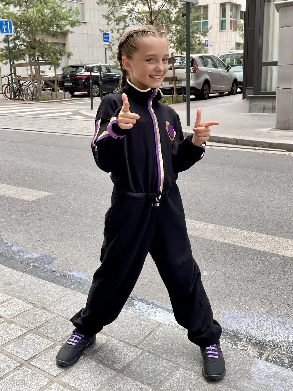 Manon Maindivide casual photo in a black tracksuit, pointing finger guns on a city street