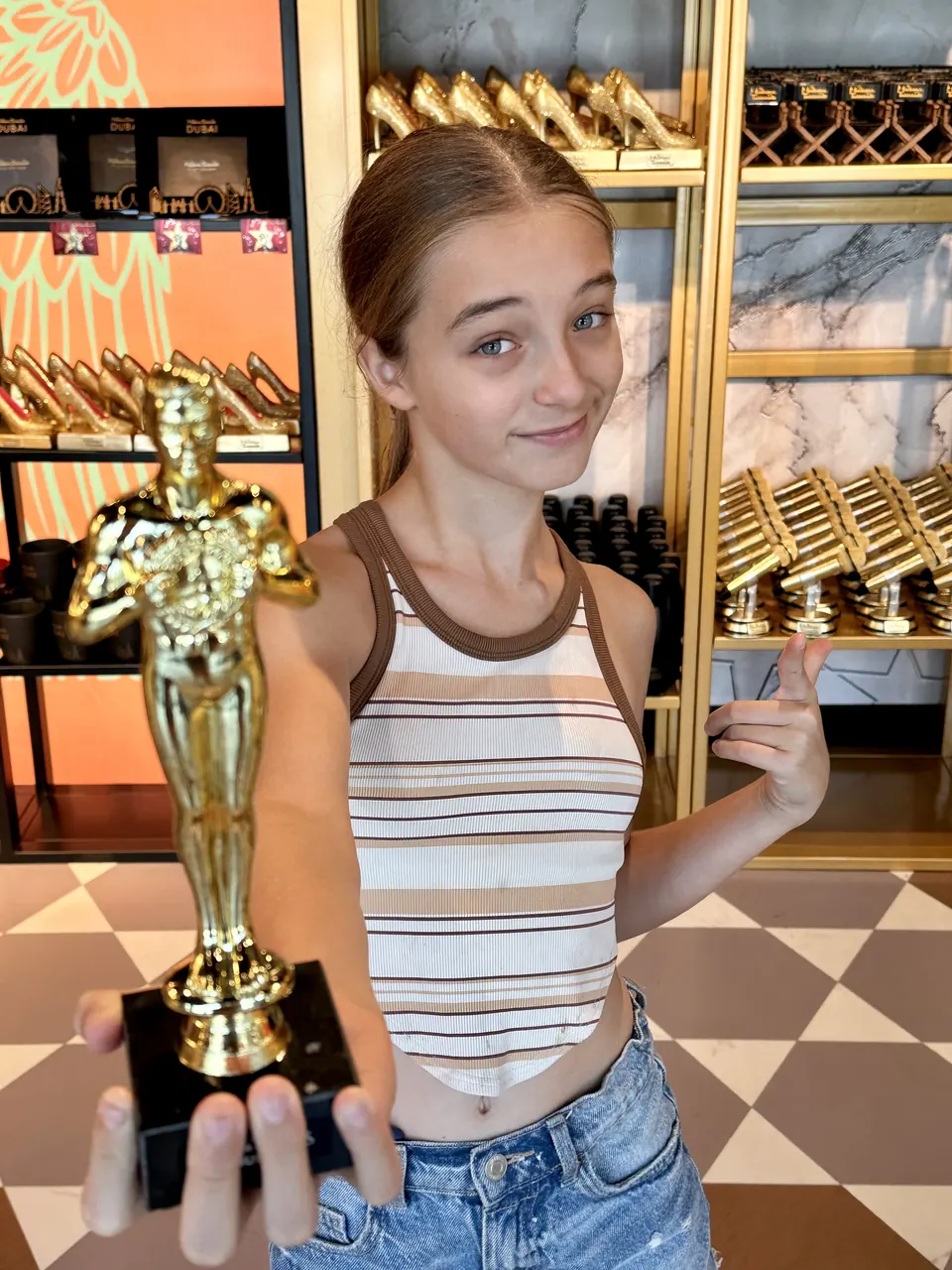 Manon Maindivide casual photo holding a golden trophy statue in a striped top, playful pose