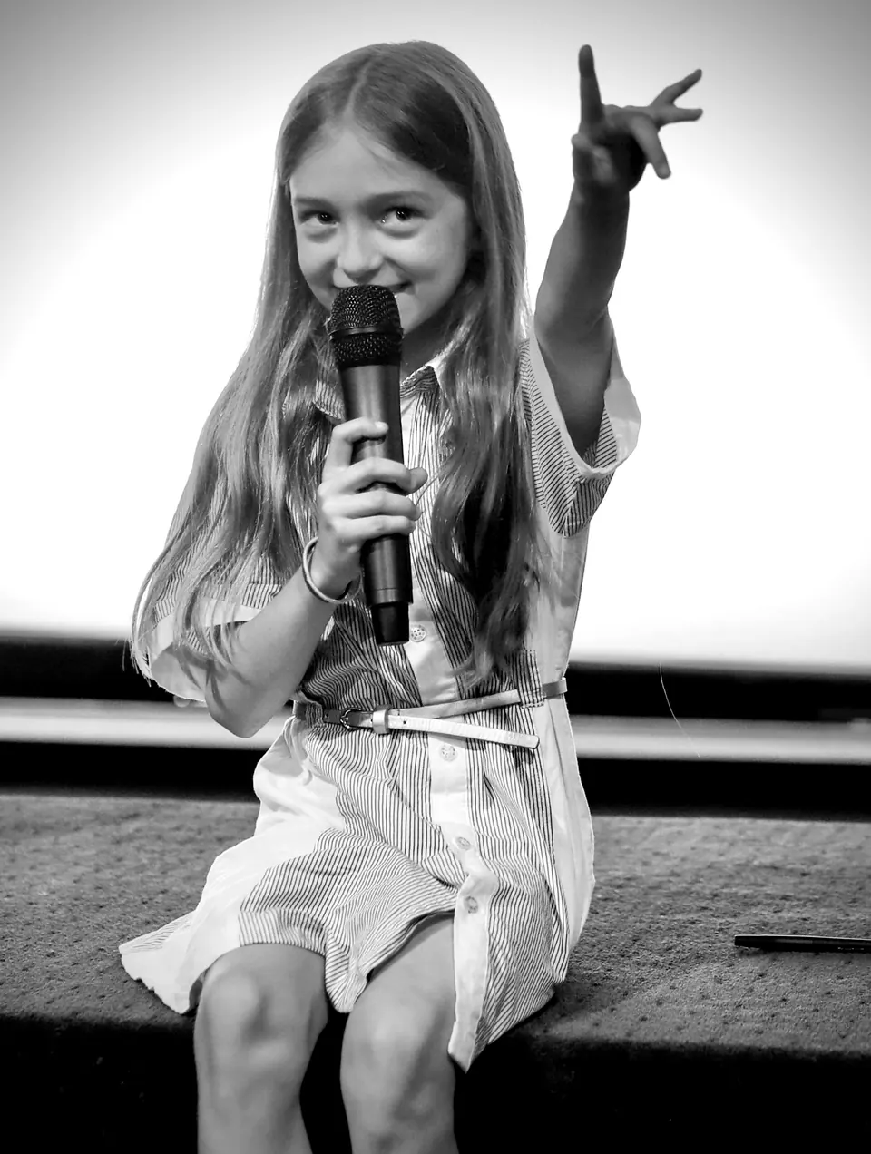 Manon Maindivide on stage in black and white, singing into a microphone with an arm raised