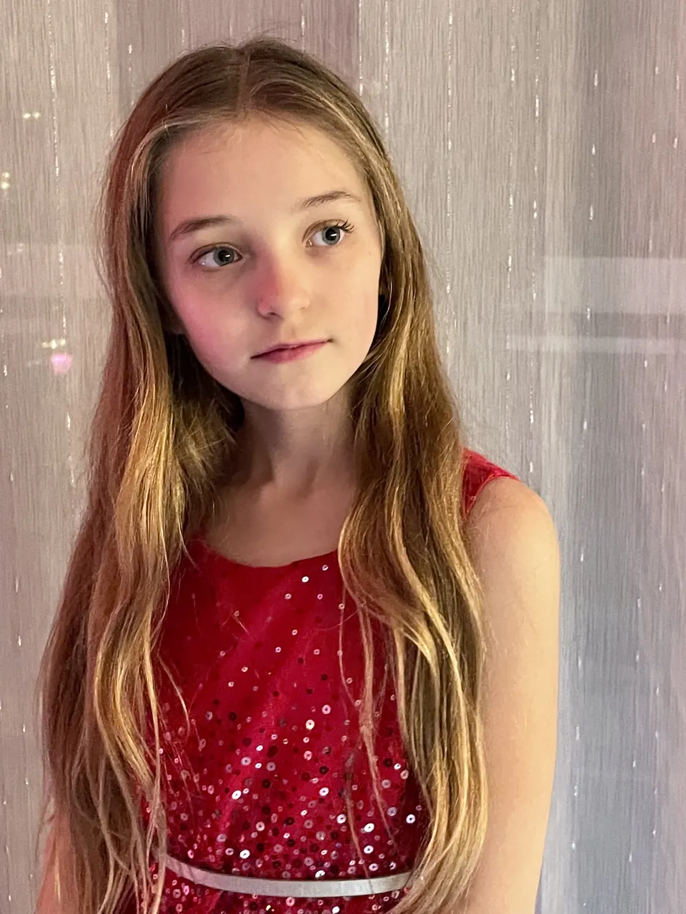 Manon Maindivide headshot in a red sequined top, looking aside against a light pink backdrop