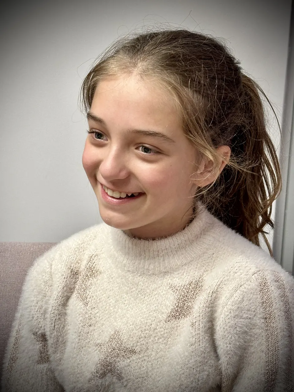 Manon Maindivide portrait in a cream knit sweater, smiling and looking away, against a light wall
