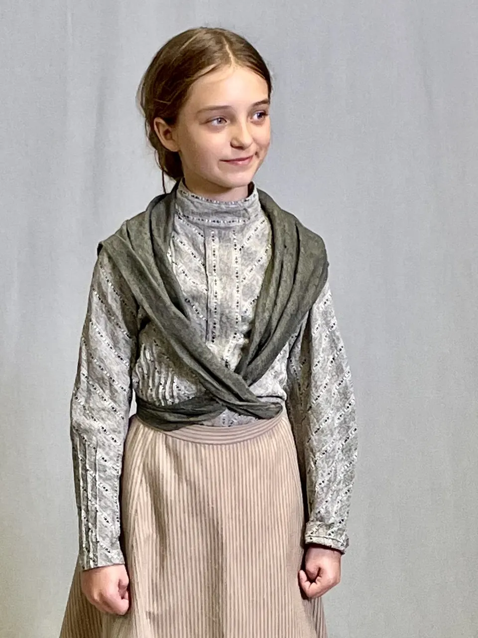 Manon Maindivide in period costume fitting, wearing a grey shawl and long beige skirt