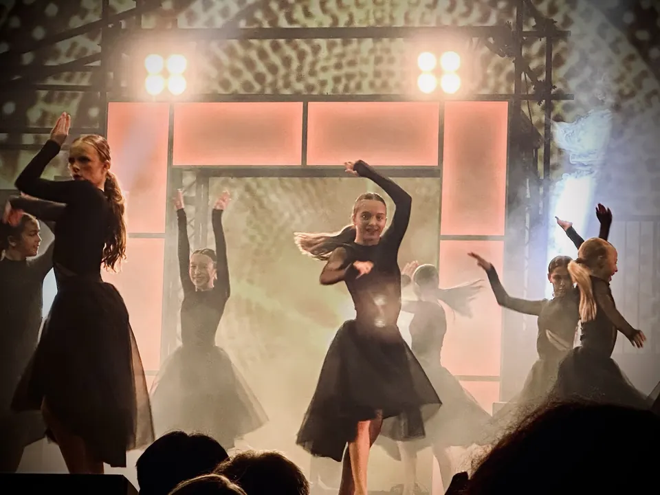 Manon Maindivide dance performance with a group in black dresses under bright stage lights