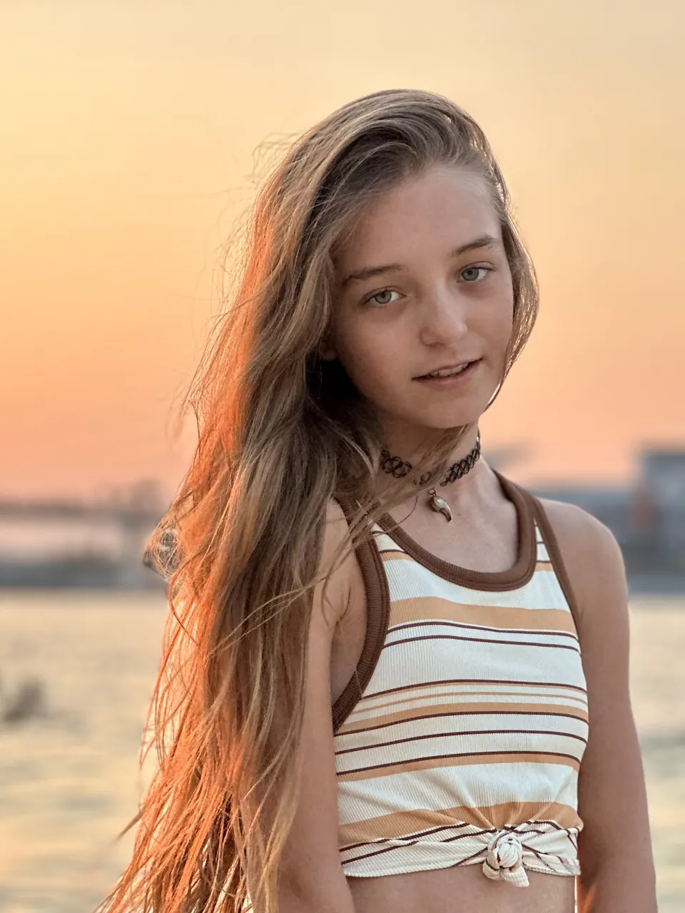 Manon Maindivide portrait at sunset in a striped crop top, long hair lit by golden light