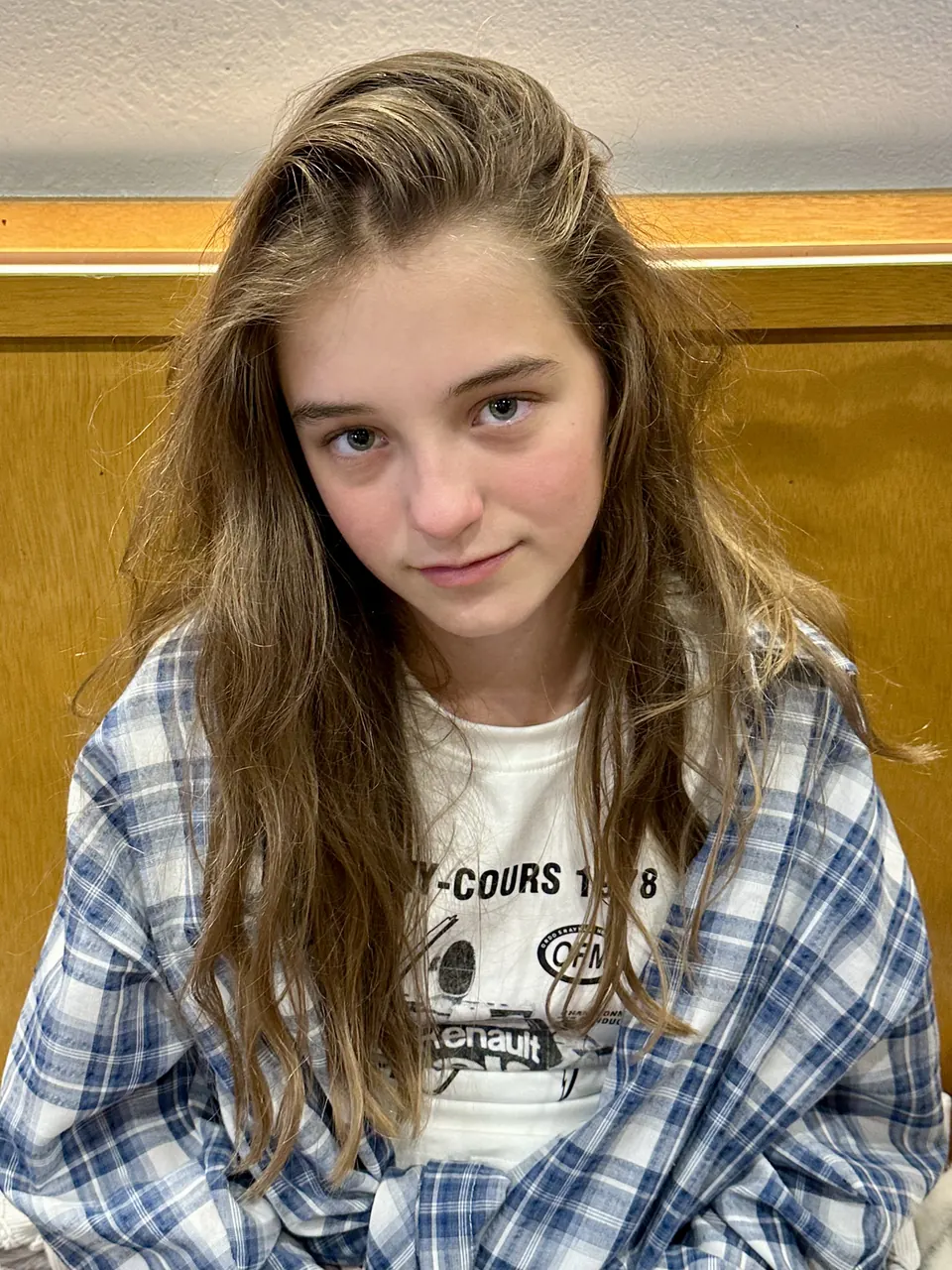 Manon Maindivide casual portrait with loose wavy hair, wearing a blue and white plaid shirt