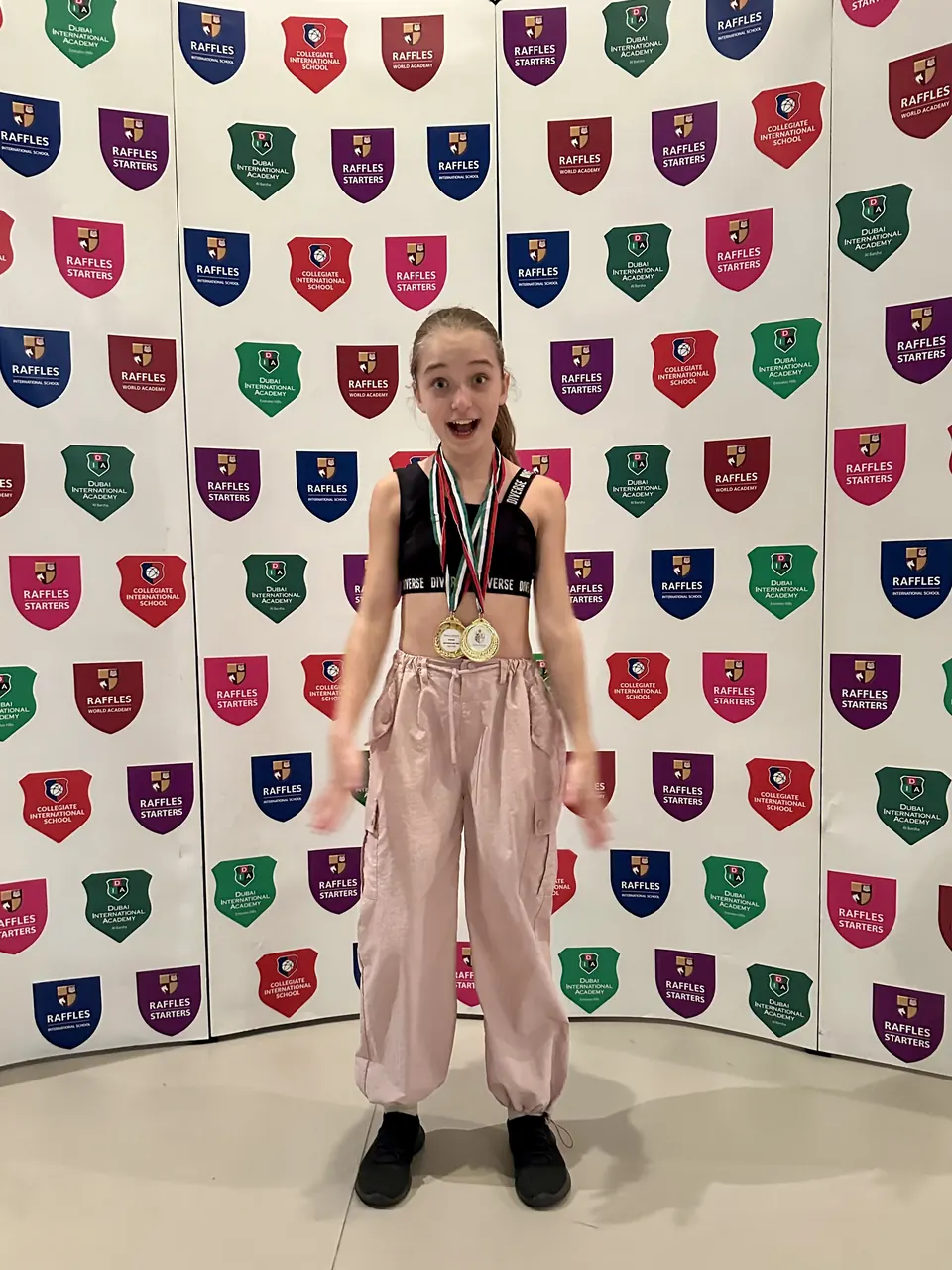 Manon Maindivide casual photo wearing medals in pink cargo pants before a logo backdrop