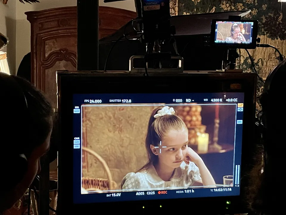Manon Maindivide on set, her scene with a white hair bow shown live on a production monitor