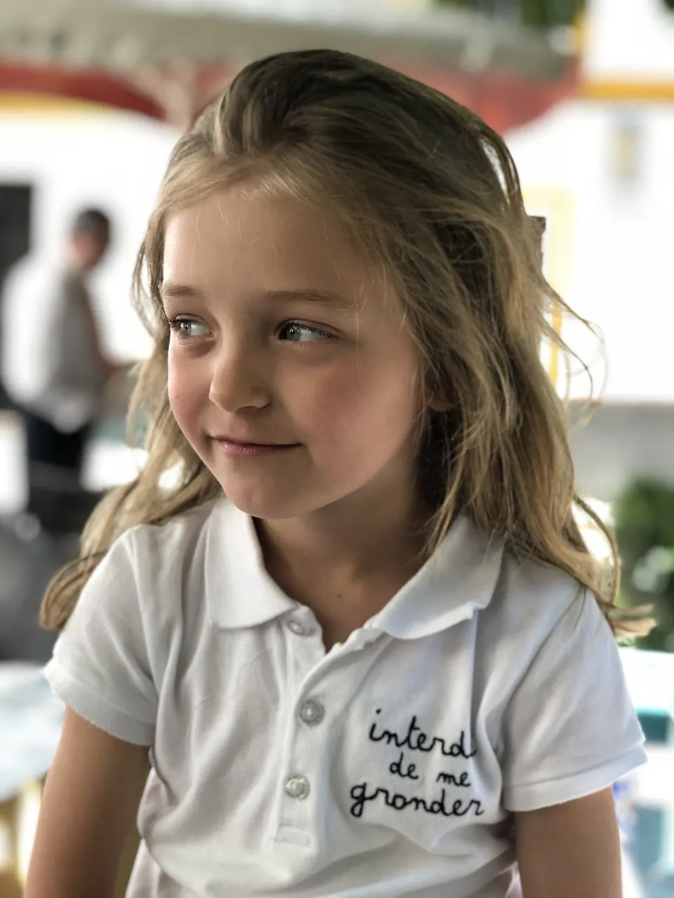 Manon Maindivide casual portrait as a young child in a white polo shirt, looking to the side