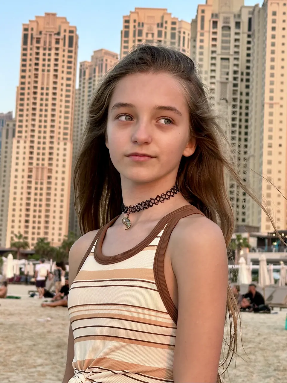 Manon Maindivide casual portrait in a striped top with tall towers behind her at dusk
