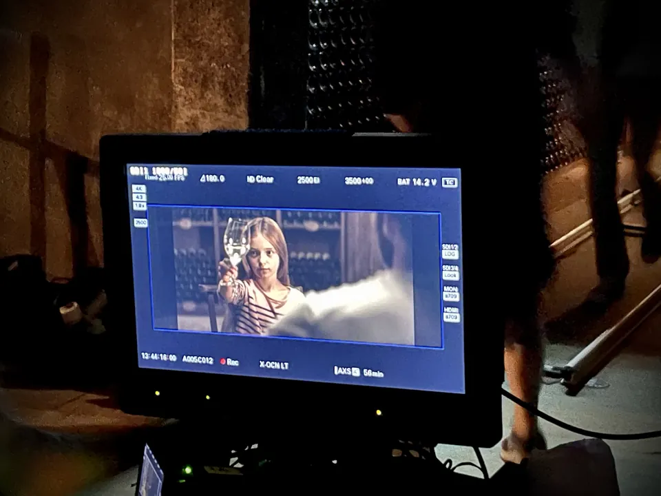 Manon Maindivide on set, seen on a camera monitor screen during filming in a dim location