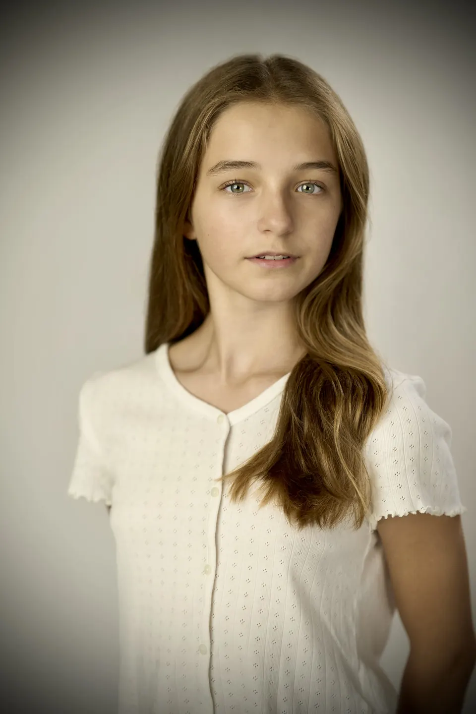 Manon Maindivide portrait in a white textured blouse, head slightly tilted, soft grey backdrop
