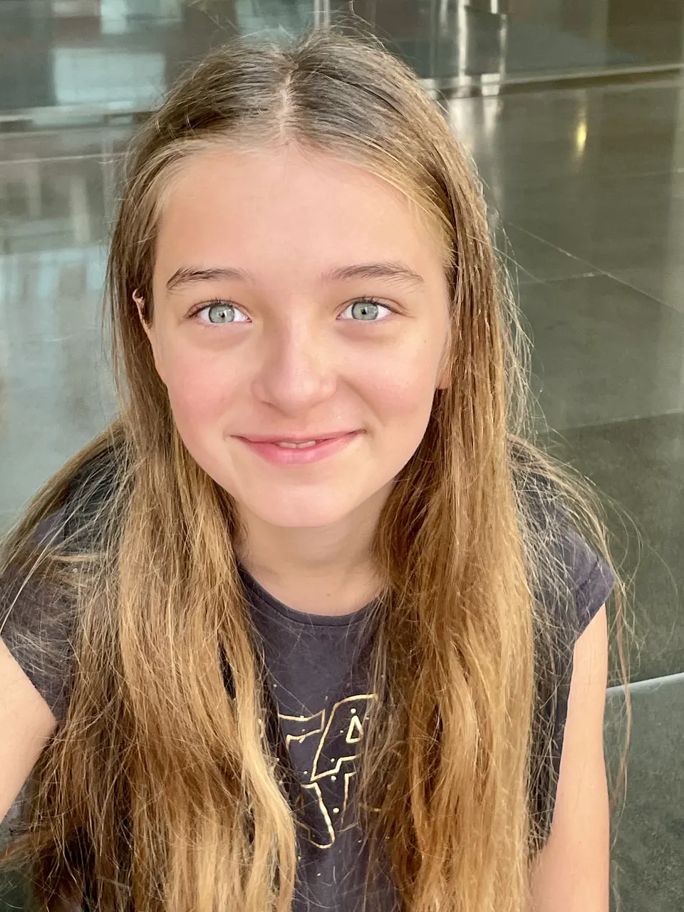 Manon Maindivide close-up portrait in a grey graphic t-shirt, gentle smile and long loose hair