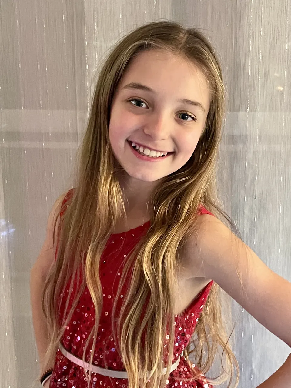 Manon Maindivide portrait smiling in a sparkly red sleeveless dress, hand on her hip