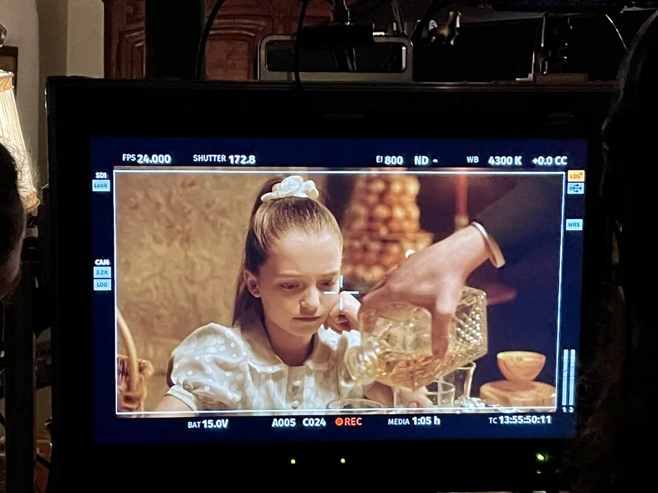 Manon Maindivide on set, a scene of her pouring from a crystal carafe seen on a monitor