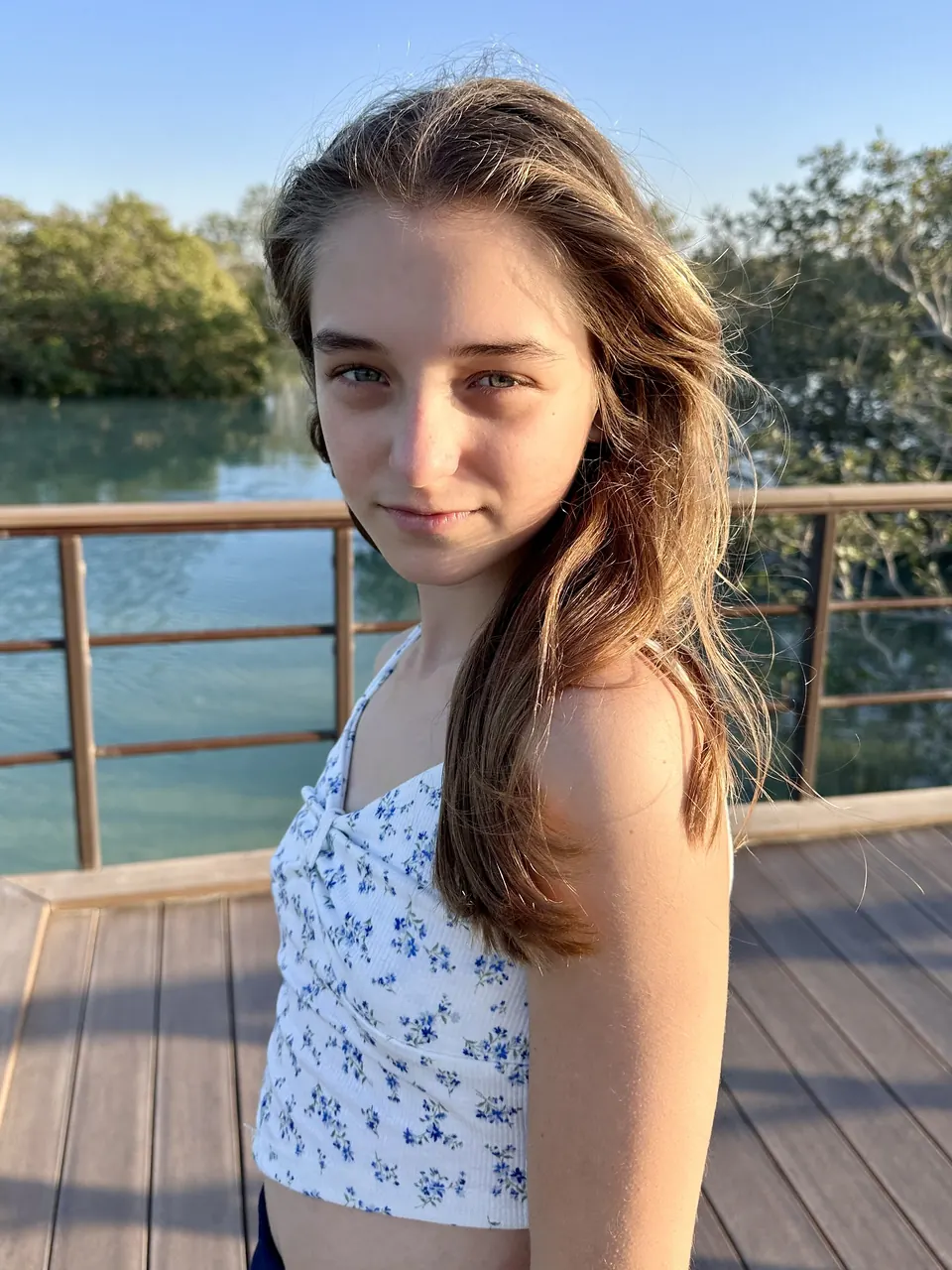 Manon Maindivide casual portrait in a white floral top on a waterside boardwalk in soft sunlight