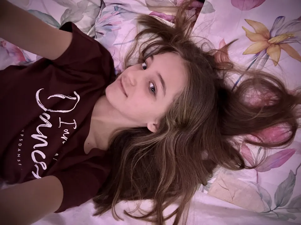 Manon Maindivide casual portrait lying on floral bedding in a dark red dance t-shirt