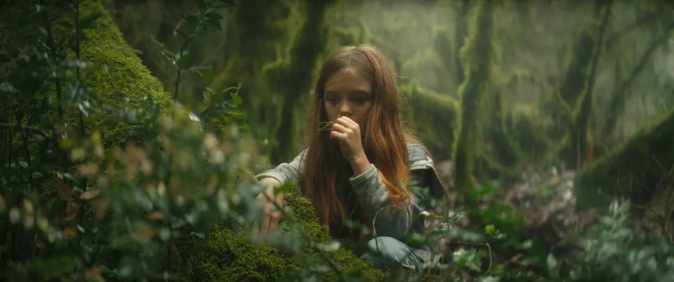 Manon Maindivide on set in a misty green forest scene, crouching among moss and ferns