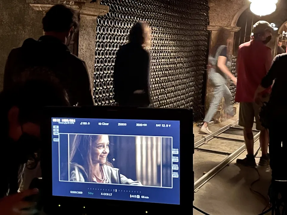Manon Maindivide on set at night, seen on a monitor while crew work in a stone wine cellar
