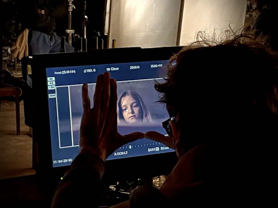 Manon Maindivide on set, a crew member watching her on a monitor in a dark room during filming