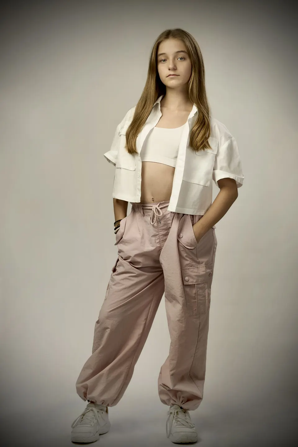 Manon Maindivide photo shoot in a white cropped shirt and pink trousers, hand in pocket
