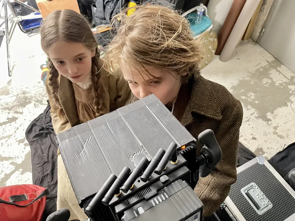 Manon Maindivide on set with braided hair, beside a young actor next to film equipment