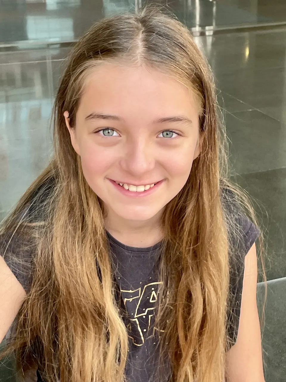 Manon Maindivide casual portrait with a bright smile, long hair and a dark grey tee