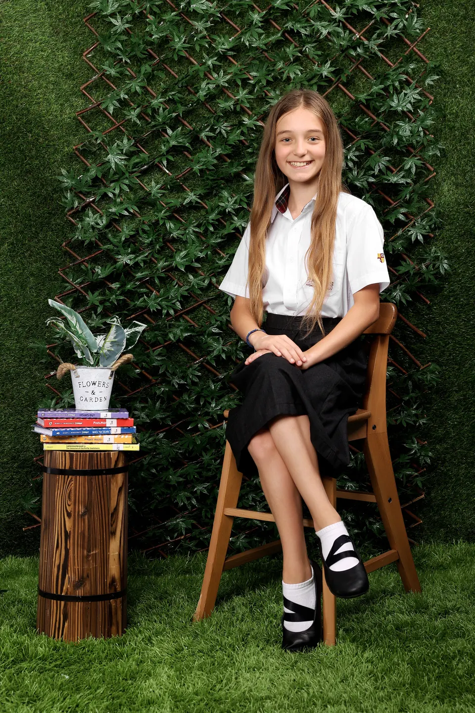 Manon Maindivide photo shoot seated on a wooden chair in a white shirt before a green wall