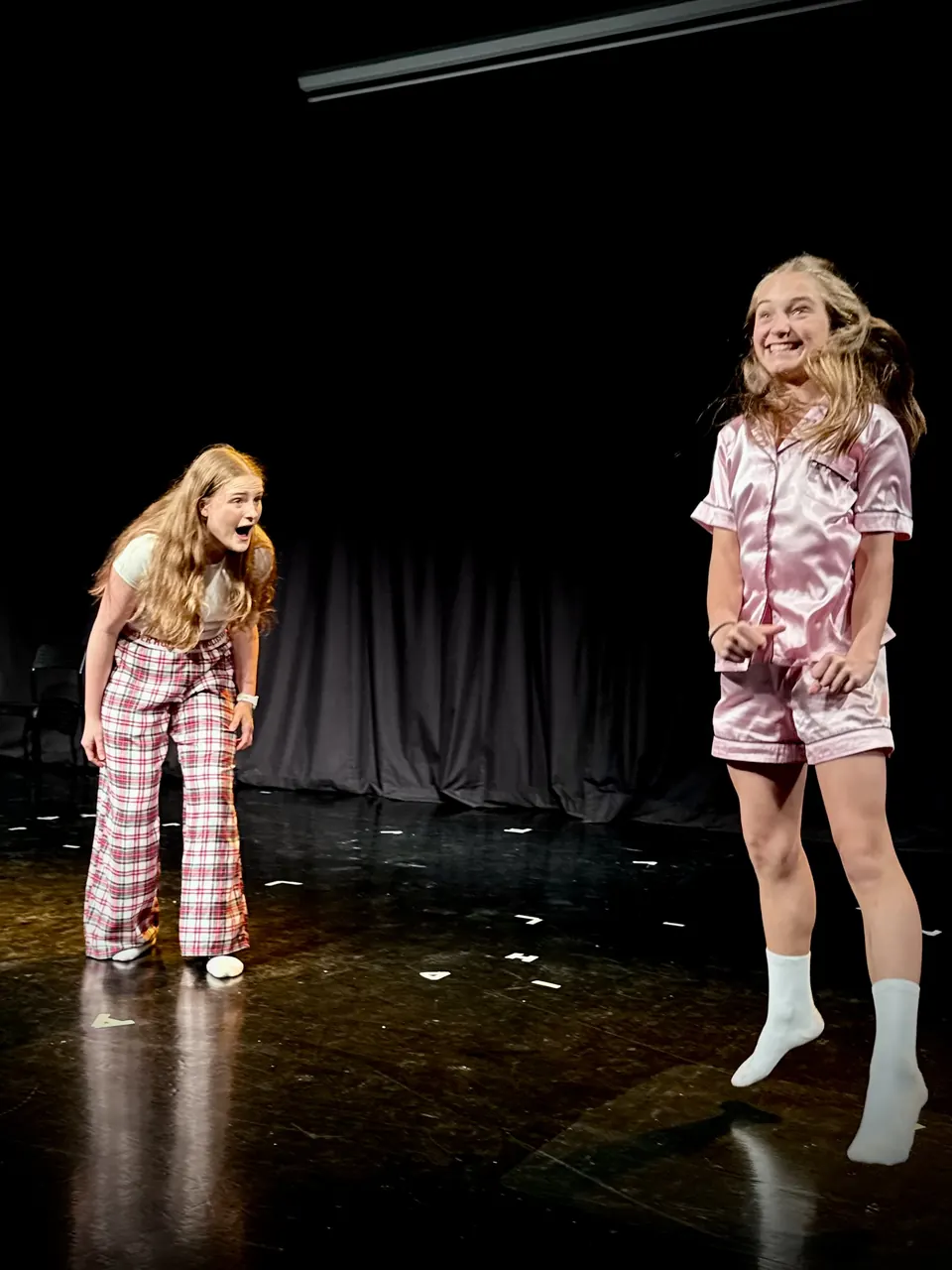 Manon Maindivide on stage in pink pyjamas facing another actress in checked trousers during a play
