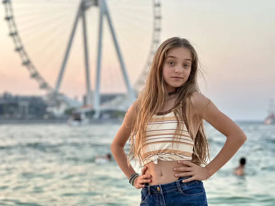 Manon Maindivide casual photo in a striped crop top by the sea with a big Ferris wheel behind