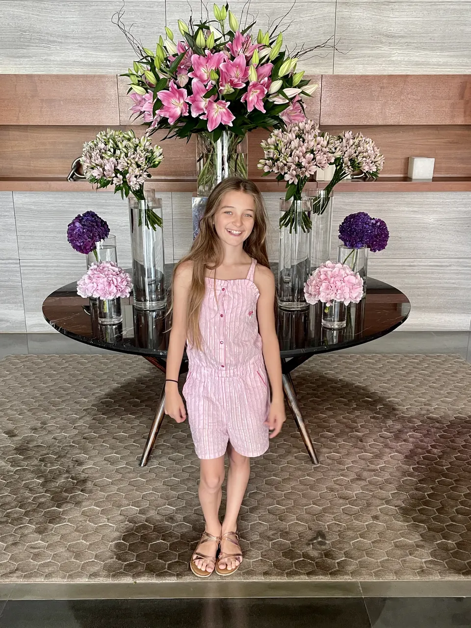 Manon Maindivide casual photo in a pink striped romper beside a large floral arrangement