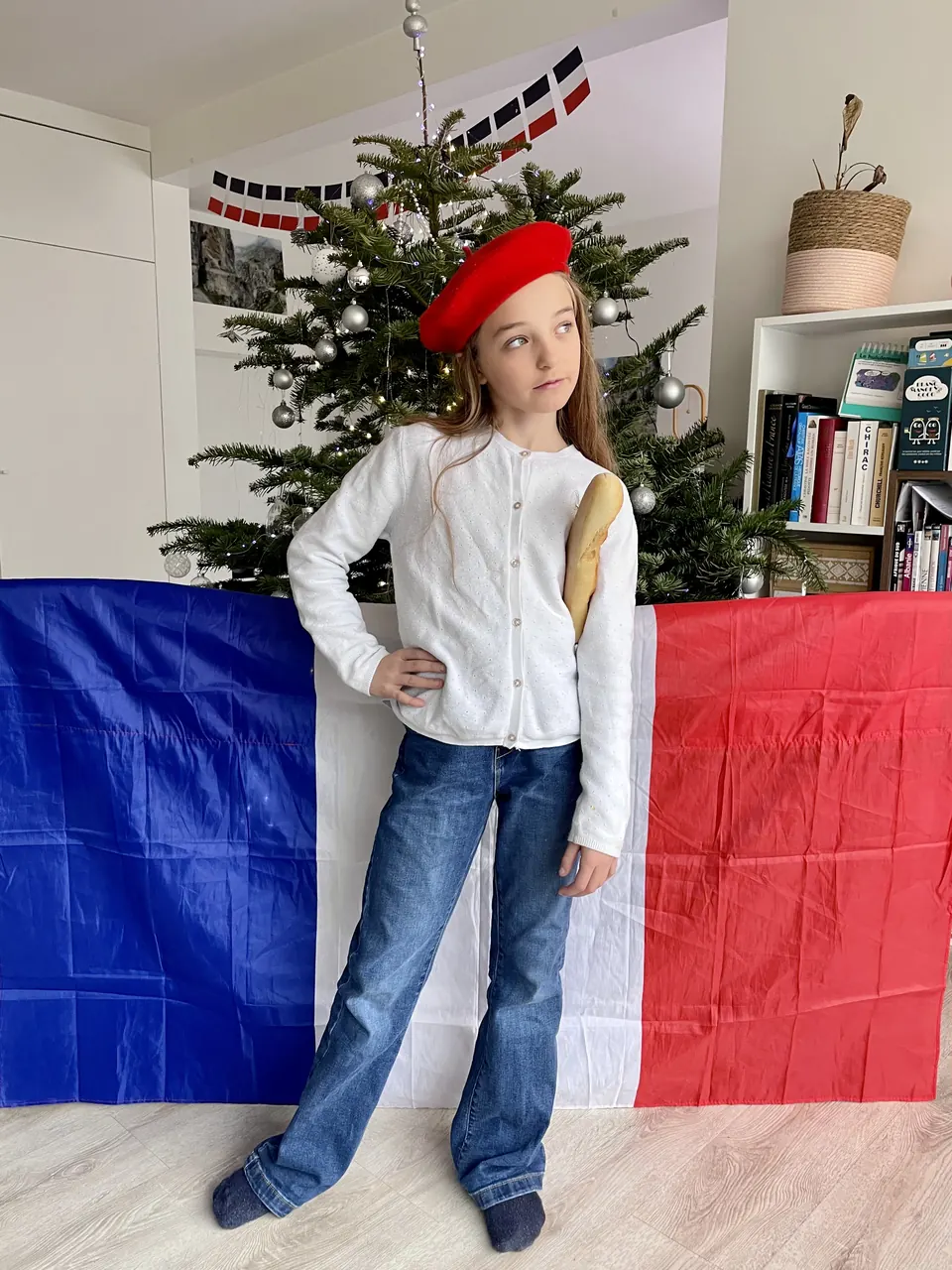 Manon Maindivide photo shoot in a red beret and jeans before a tricolour flag and a Christmas tree